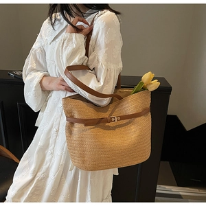 Gros plan détaillé d'un sac cabas en paille tissée avec lanières en cuir et boucles en métal