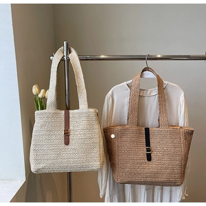 Detail of large woven straw tote bags in beige and brown hanging in a summer resort setting