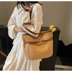 Détail du sac cabas en paille tressée avec bandoulières en cuir brun et boucle en métal