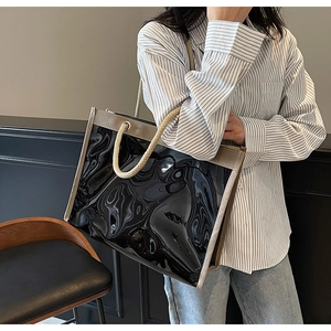 Detail of glossy black PVC tote bag with thick rope handles and contrast fabric edging