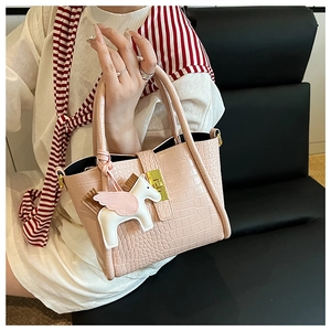 Dettaglio borsa a secchiello rosa coccodrillo con fibbia dorata e ciondolo a forma di pony