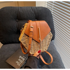 Detail of hexagonal woven straw bag with brown leather flap and golden tassel charm