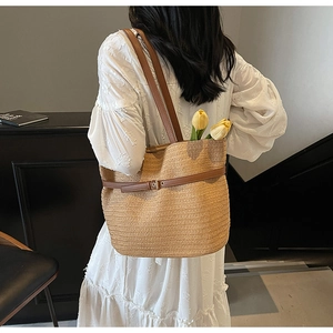 Sac cabas en paille tressée avec lanières en cuir marron porté par un mannequin de dos