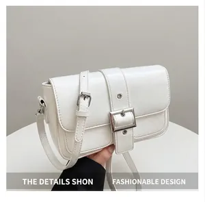 Détail d'un sac bandoulière blanc texturé avec une boucle carrée en métal argenté chic