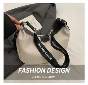 Détail du sac hobo blanc cassé en cuir grainé avec bandoulière tissée et logo lettré