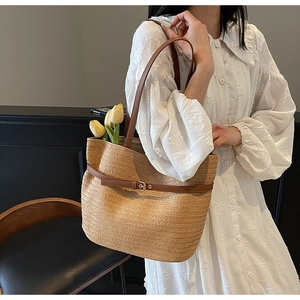 Détail du sac cabas en paille tressée avec bandoulière en cuir brun et boucle dorée