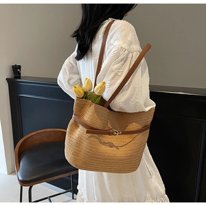 Détail d'un grand cabas en paille tressée avec lanières en cuir brun et fleurs tulipes