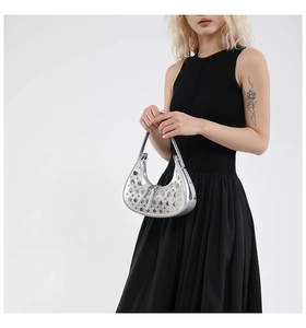 Sac croissant argenté avec rivets porté sur une robe noire minimaliste au style moderne