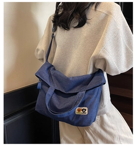 Close-up of a large blue denim tote bag with decorative cartoon patches and handles