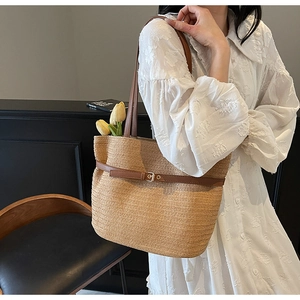 Détail d'un grand sac cabas tissé avec anses en cuir brun porté par un mannequin
