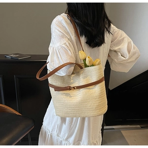 Détail du sac fourre-tout tissé beige avec lanières en cuir marron et boucles métalliques