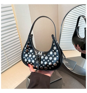 Detail of silver rivets on black hobo bag with mirror reflection of the half-moon shape