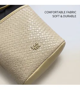 Gros plan du sac à main tissé beige avec logo en métal doré et finitions en cuir lisse