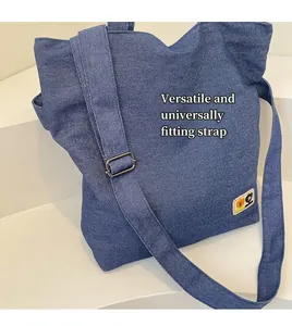 Detail of blue denim canvas tote featuring adjustable strap and cute cartoon embroidery