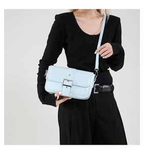 Sac à bandoulière bleu clair avec boucle argentée porté par un mannequin en studio
