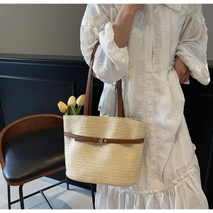 Détail du sac cabas en paille tissée avec lanières en cuir marron et boucle de style rétro