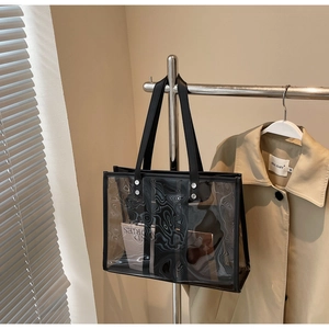 Détail du sac cabas transparent avec texture ondulée et anses noires sur un cintre
