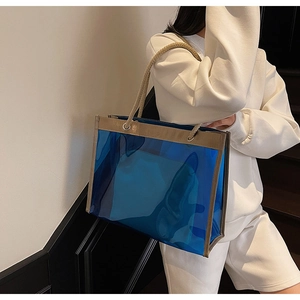 Detail of blue transparent PVC tote bag with beige woven handles on model's shoulder
