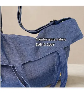 Detail of dark blue denim crossbody bag featuring textured fabric and adjustable metal buckle
