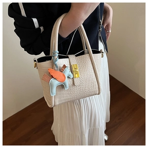Dettaglio borsa a secchiello beige goffrata coccodrillo con chiusura dorata e ciondolo colorato