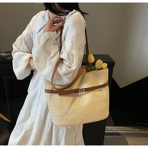 Détail du sac fourre-tout en paille tissée avec lanières en cuir sur robe à fleurs