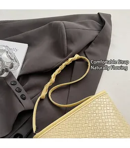 Gros plan du sac seau tissé crème avec bandoulière torsadée sur un blazer gris