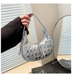 Gros plan détaillé d'un sac demi-lune argenté avec des rivets métalliques et un zip