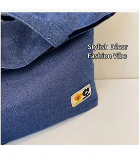 Detail of dark blue denim bag showing rectangular cartoon embroidery and clean stitching