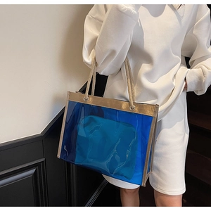 Detail of transparent blue PVC tote bag with gold trim and beige woven rope handles