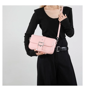 Détail d'un sac à bandoulière rose en similicuir avec une grande boucle argentée