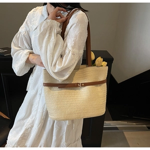 Détail d'un grand sac cabas en paille tressée beige avec anses en cuir marron