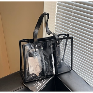 Detail of transparent PVC tote bag with black leather handles and interior pouch