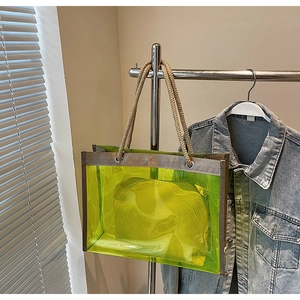 Detail of neon green transparent PVC tote with woven rope handles and inner pouch