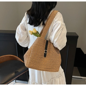 Detail of hand-woven straw tote bag with black leather buckle strap and large capacity