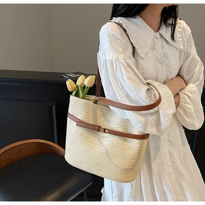 Détail du sac cabas en paille d'été avec lanières en cuir marron et boucle métallique