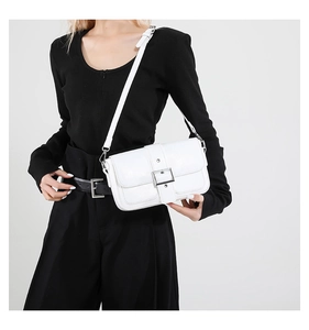 Gros plan d'un sac bandoulière blanc en cuir grainé avec boucle argentée sur habit noir