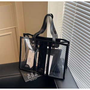 Detail of transparent PVC tote bag with black leather trim and matching inner pouch