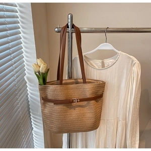 Vue détaillée du sac cabas en paille avec lanières en cuir marron et boucle métallique
