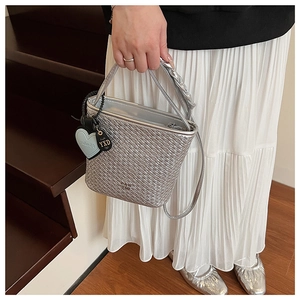 Détail du sac seau tissé argenté avec texture métallique et pendentif en forme de cœur