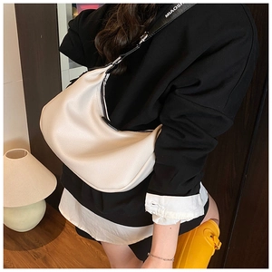 Détail du cuir grainé litchi et de la large bandoulière lettrée du sac croissant crème