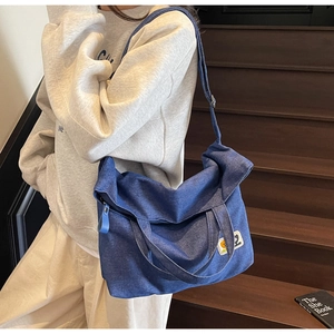 Detail of dark blue denim tote bag with cartoon patches and wide strap on wooden steps