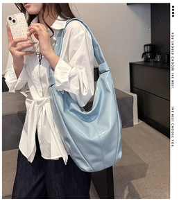 Détail du sac hobo en cuir verni bleu clair montrant sa texture brillante et son design