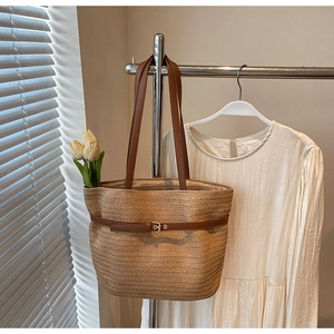 Détail du sac cabas en paille tressée avec anses en cuir marron et boucle métallique