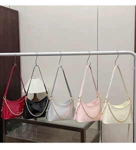 Detail view of five shiny patent leather crescent bags in various colors with gold chains