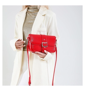 Détail du sac bandoulière en cuir rouge brillant avec boucle carrée argentée et fine bandoulière