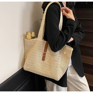 Close-up of beige woven tote bag with brown leather strap detail and tulip decoration