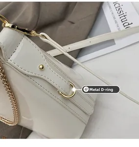 Detail shot of the gold D-ring hardware and stitching on the white patent leather bag
