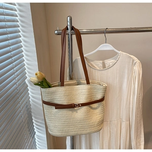 Détail du sac cabas tissé avec anses en cuir marron et boucle métallique décorative