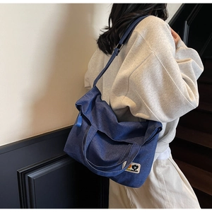 Deep blue denim tote bag with floral patch shown on shoulder for size and drape reference