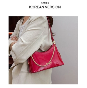 Detail of red patent leather hobo bag featuring gold chain strap and polished finish